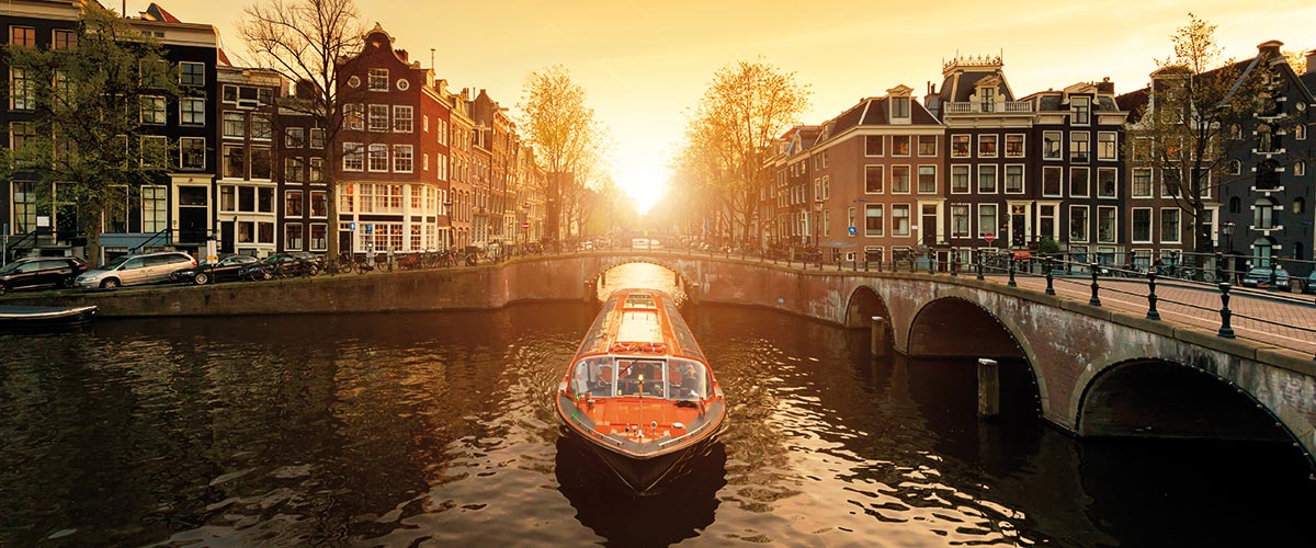 A tourist canal boat in Amsterdam at sunset